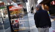 A local resident looks at a billboard with pictures of supporters of US President Donald Trump wanted by the FBI who participated in storming the U.S. Capitol in Washington, U.S., January 13, 2021. Reuters/Carlos Barria