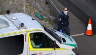 A police officer watches an entrance to a quarantine hotel, where returning travelers are kept in isolation for a period to curb the spread of the coronavirus disease (COVID-19), as a patient transport service vehicle departs in Sydney, Australia, August 