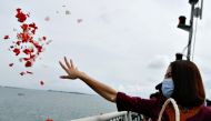 A colleague of the crew of Sriwijaya Air flight SJ 182, which crashed into the sea, throws flowers and petals from the deck of Indonesia's Naval ship KRI Semarang as they visit the site of the crash to pay their tribute, at the sea off the Jakarta coast, 