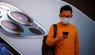 FILE PHOTO: A man wears a face mask while waiting at an Apple Store before Apple's 5G new iPhone 12 go on sale, as the coronavirus disease (COVID-19) outbreak continues in Shanghai China October 23, 2020. REUTERS/Aly Song/File Photo

