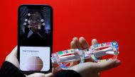 An employee of online fashion retailer Zozo Inc, poses with Zozoglass and its smartphone application, used to measure skin tone for ordering cosmetics online, during a demonstration at the company's office in Tokyo, Japan, January 28, 2021. Picture taken 