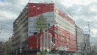 Cars drive past a building painted with the flag of Lebanon at al-Nour square, as they are pictured through rain drops on a car window, amid the spread of the coronavirus disease (COVID-19), in Tripoli, Lebanon January 29, 2021. REUTERS/Mohamed Azakir