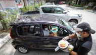 A waiter serves a customer outside Padi House restaurant for 'dine in car' service, during a lockdown due to the coronavirus disease (COVID-19) outbreak, in Cyberjaya, Malaysia February 4, 2021. REUTERS/Lim Huey Teng