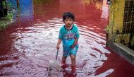 A girl walks through a flooded road with red water due to the dye-waste from cloth factories, in Pekalongan, Central Java province, Indonesia, February 6, 2021 in this photo taken by Antara Foto. Antara Foto/Harviyan Perdana Putra/ via Reuters 