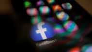 Facebook logo displayed on a mobile phone is seen through a magnifying glass in this picture illustration taken February 9, 2021. REUTERS/Carlos Jasso

