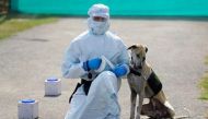 An army soldier wearing personal protective equipment (PPE) sits next to a military dog after a demonstration of the dog on how to detect the coronavirus disease (COVID-19), at an army veterinary hospital in New Delhi, India, February 9, 2021. REUTERS/Adn