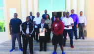 Kenya’s Ambassador to Qatar, H E Paddy C Ahenda, poses with the QSM trophy alongside strongest man athletes and embassy staff.