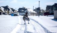 FILE PHOTO: A man walks to his friend's home in a neighborhood without electricity as snow covers the BlackHawk neighborhood in Pflugerville, Texas, U.S. February 15, 2021. Bronte Wittpenn/Austin American-Statesman/USA Today Network via REUTERS/File Photo