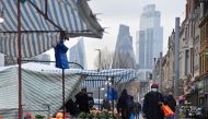 FILE PHOTO: People shop at market stalls, with skyscrapers of the CIty of London financial district seen behind, amid the coronavirus disease (COVID-19) pandemic, in London, Britain, January 15, 2021. REUTERS/Toby Melville