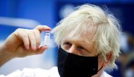 FILE PHOTO: Britain's Prime Minister Boris Johnson holds a vial of an Oxford-AstraZeneca COVID-19 vaccine, during his visit at a vaccination centre at Cwmbran Stadium in Cwmbran, south Wales, Britain February 17, 2021. Geoff Caddick/Pool via REUTERS/File 