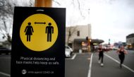 People jog past a social distancing sign on the first day of New Zealand's new coronavirus disease (COVID-19) safety measure that mandates wearing of a mask on public transport, in Auckland, New Zealand, August 31, 2020. REUTERS/Fiona Goodall//File Photo