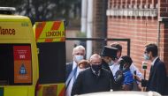 Hospital staff and people holding umbrellas stand next to an ambulance outside King Edward VII's Hospital, where Britain's Prince Philip was admitted in London, Britain, March 1, 2021. REUTERS/Henry Nicholls
