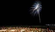 People standing near candles watch as fireworks light up the sky to mark the 10th anniversary of the 2011 earthquake and tsunami that killed thousands and triggered the worst nuclear accident since Chernobyl in Futaba, Fukushima prefecture, Japan, March 1