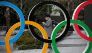 FILE PHOTO: A man looks at his mobile phone next to The Olympic rings in front of the Japan Olympics Museum in Tokyo, Japan, March 4, 2020. REUTERS/Stoyan Nenov//File Photo