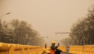A road worker uses his smartphone in Beijing, China, as the city is shrouded in haze after a sandstorm, March 15, 2021. REUTERS/Thomas Peter