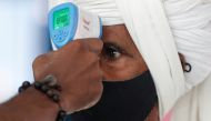  A health worker uses an infrared thermometer to check the temperature of a passenger amid the spread of the coronavirus disease (COVID-19), at a railway station in Mumbai, India, March 21, 2021. REUTERS/Francis Mascarenhas/File Photo