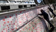 Volunteers and relatives of bereaved paint hearts along a wall beside St Thomas' hospital as a memorial to all those who have died so far in the UK from COVID-19, amid the spread of the coronavirus disease pandemic in London, Britain, March 29, 2021. REUT