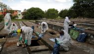 Gravediggers wearing protective suits close bags with bones during exhumations to open space on cement graves as new burials are suspended, except private deposits and children, at Vila Nova Cachoeirinha cemetery amid the outbreak of the coronavirus disea