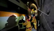 Rescue workers walk next to a damaged train which derailed in a tunnel north of Hualien, Taiwan April 2, 2021, in this still image taken from video. FTV via REUTERS ATTENTION EDITORS - THIS IMAGE WAS PROVIDED BY A THIRD PARTY. NO RESALES. NO ARCHIVES. TAI