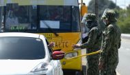 Police officers check an ID of a motorist passing a checkpoint as the country's capital returns to stricter lockdown measures amid rising coronavirus disease (COVID-19) cases, in Quezon City, Metro Manila, Philippines, March 29, 2021. REUTERS/Lisa Marie D