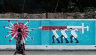A woman wearing a protective face mask walks past a graffiti, amidst the spread of the coronavirus disease (COVID-19), on a street in Mumbai, India, March 30, 2021. REUTERS/Francis Mascarenhas