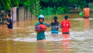A man wearing a helmet carries his goods through the water in an area affected by floods after heavy rains in Dili, East Timor, April 4, 2021. REUTERS/Lirio da Fonseca