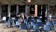 Workers clean chairs to open a restaurant terrace on the first day of the reopening after a country lockdown, amid the coronavirus disease (COVID-19) pandemic, in Lisbon, Portugal, April 5, 2021. REUTERS/Pedro Nunes