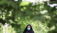 A woman looks at her mobile phone on a street in Tehran, following the tightening of restrictions to curb the surge of COVID-19 cases, Iran April 10, 2021. Majid Asgaripour/WANA