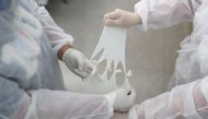 Nursing technician Semei Araujo Cunha and nurse Vanessa Fermenton tie up gloves to make what they call 'maozinha do amor' or 'hands of love', gloves filled with warm water to use on coronavirus disease (COVID-19) patients intubated at a UPA (Emergency Ser