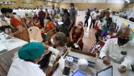 A woman receives a dose of COVISHIELD, a coronavirus disease (COVID-19) vaccine manufactured by Serum Institute of India, as others wait for their turn at a vaccination centre in Mumbai, India, April 26, 2021. REUTERS/Niharika Kulkarni
