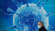 A man wearing a protective face mask walks past an illustration of a virus outside a regional science centre amid the coronavirus disease (COVID-19) outbreak, in Oldham, Britain August 3, 2020. REUTERS/Phil Noble/File Photo