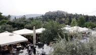 People walk near an outdoor cafe in Thiseio, as restaurants and cafes in Greece open after six months of lockdown, amid the coronavirus disease (COVID-19) outbreak, in Athens, Greece, May 3, 2021. REUTERS/Louiza Vradi