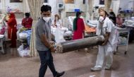 Relatives of a woman suffering from the coronavirus disease (COVID-19), carry an oxygen cylinder as she receives treatment in the emergency room of Holy Family Hospital in New Delhi, India, May 1, 2021. REUTERS/Danish Siddiqui SEARCH 