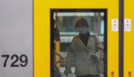 A passenger wearing a protective face mask boards a train after new public health regulations were announced for greater Sydney, including compulsory mask-wearing on public transport, following the emergence of new cases of the coronavirus disease (COVID-