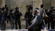 A Palestinian man prays as Israeli police gather during clashes at the compound that houses Al-Aqsa Mosque in Jerusalem's Old City on May 7, 2021. (Reuters/Ammar Awad)