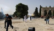 Palestinians run away as Israeli police fire a stun grenade during clashes at the compound that houses Al-Aqsa Mosque, in Jerusalem's Old City, May 10, 2021. REUTERS/Ammar Awad