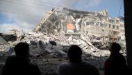 Palestinians look at the remains of a tower building which was destroyed by Israeli air strikes, amid a flare-up of Israeli-Palestinian violence, in Gaza City May 13, 2021. Reuters/Suhaib Salem
