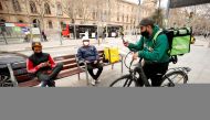 Delivery riders with backpacks wait for orders at Universitat square in Barcelona, Spain. (REUTERS/Albert Gea/File Photo)