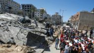 Mourners carry the bodies of Palestinians, including members of Abu Hatab family, who were killed amid a flare-up of Israeli-Palestinian violence, during their funeral near the remains of a building destroyed in Israeli air strikes, at the Beach refugee c