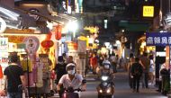 People wearing protective face masks ride their motorbikes as others shop at a night market in Taipei, Taiwan, May 15, 2021. REUTERS/Ann Wang
