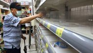 A man takes instant noodles from a near-empty shelf as customers rush to buy their groceries after the government advised people to reduce leaving their homes and limit gatherings due to an increasing number of locally transmitted coronavirus disease (COV