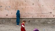 Children stand next to a damaged wall at the site of a car bomb blast in Kabul, Afghanistan May 10, 2021. REUTERS/Stringer/File Photo