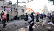 People walk past debris in a street at the site of Israeli air strikes, in Gaza City May 16, 2021. REUTERS/