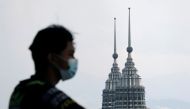 A man wearing a protective mask looks on as the Petronas Twin Towers are seen in the background, amid the the coronavirus disease (COVID-19) pandemic, in Kuala Lumpur, Malaysia April 12, 2021. REUTERS/Lim Huey Teng/File Photo