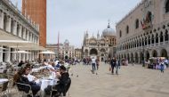 People sit at outdoor tables at St. Mark's Square as Italy lifts quarantine restrictions for travellers arriving from European Union countries, Britain and Israel and begins offering COVID-free flights in a bid to revive the tourism industry, in Venice, I