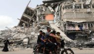 Palestinians ride a motorcycle past the site of an Israeli air strike, after Israel- Hamas truce, in Gaza May 21, 2021. REUTERS/Suhaib Salem