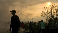 Residents walk near destroyed homes with the smouldering lava deposited by the eruption of Mount Nyiragongo volcano near Goma, in the Democratic Republic of Congo May 23, 2021. REUTERS/Djaffar Al Katanty 