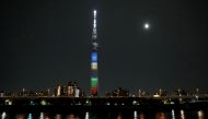 A supermoon, the biggest and brightest full moon of the year, shines next to the Tokyo Skytree which is illuminated with colors of the Tokyo 2020 Olympic Games, in Tokyo, Japan May 26, 2021. REUTERS/Issei Kato
