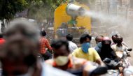 File photo: People wearing face maks ride motorcycles as a municipal vehicle decontaminates a road during a 21-day nationwide lockdown to slow the spreading of coronavirus disease (COVID-19), in Chennai, India, April 9, 2020. Reuters/P. Ravikumar/File Pho