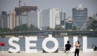 A woman wearing a mask amid the coronavirus disease (COVID-19) pandemic takes photographs of her boyfriend at a Han river park in Seoul, South Korea, May 24, 2021. Reuters/Kim Hong-Ji